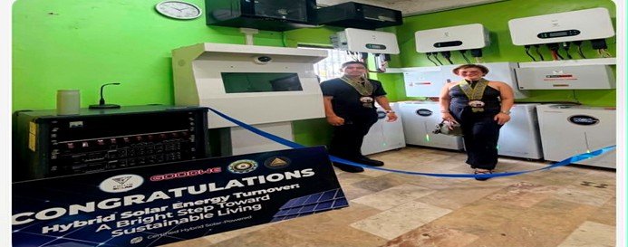 Solar Shift team beside a battery bank at a system turnover, with a congratulations banner