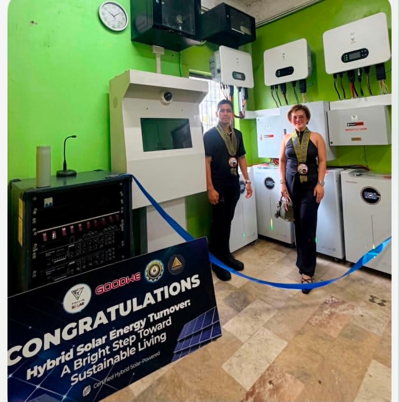 Two team members beside battery storage and inverters at a system turnover